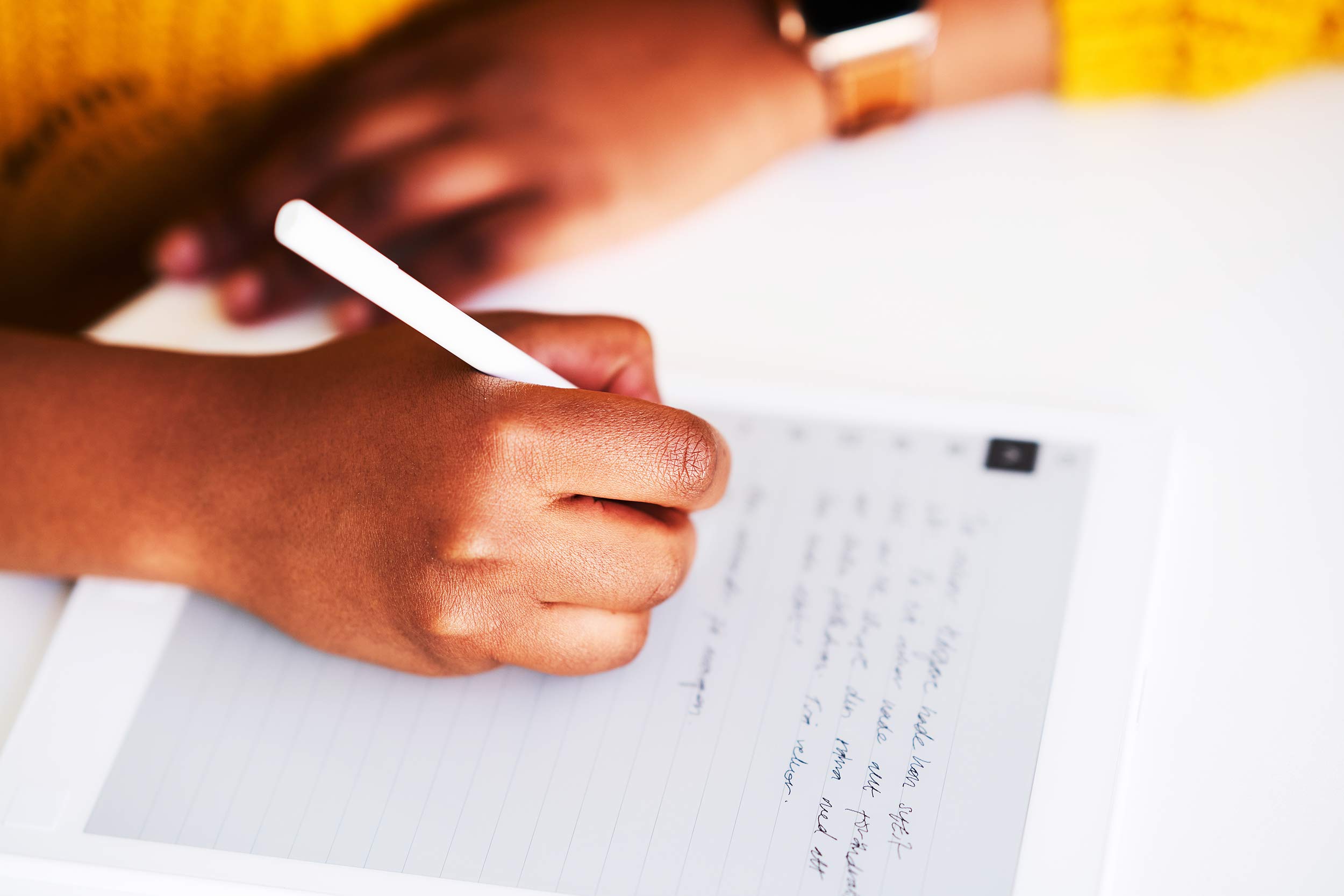 Närbild på Mary Benadets hand när hon skriver med papper och penna.