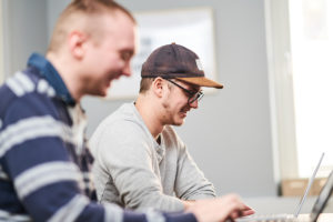 Två personer sitter tillsammans och jobbar vid en dator.