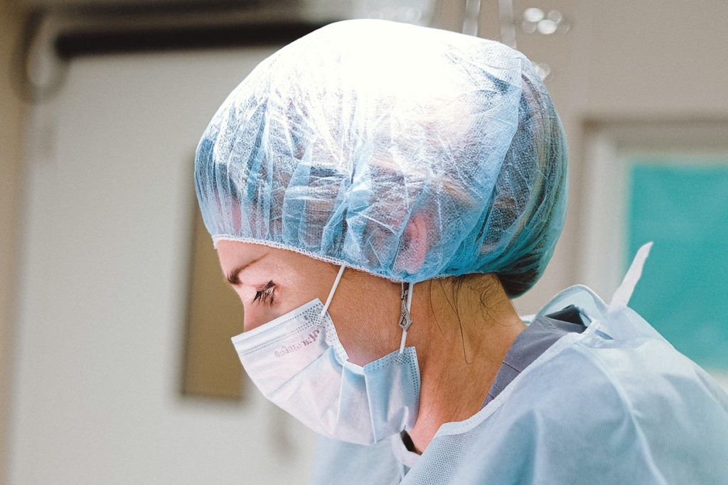 En kirurg i skyddsmössa och ansiktsmask
