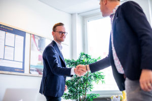 Gustav Österström som jobbar med investeringsfonden Spectria Invest skakar hand med en person efter ett möte om att finansiera företag.