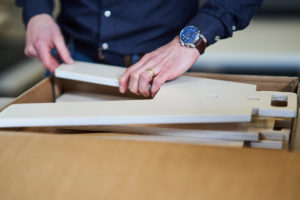 Bilden visar två händer som håller i en trämodul som ska sättas ihop till en möbel.