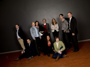 Science Park-teamet 2011. Medarbetarne står tillsammans i ett mörkt rum och är belysta med spotlight.