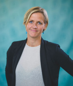 Helen Nordström, VD på Placebrander, står framför en turkosfärgad studiobakgrund.