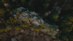 Ett berg omringat av skog. Fotot är taget i fågelperspektiv med en drönare.