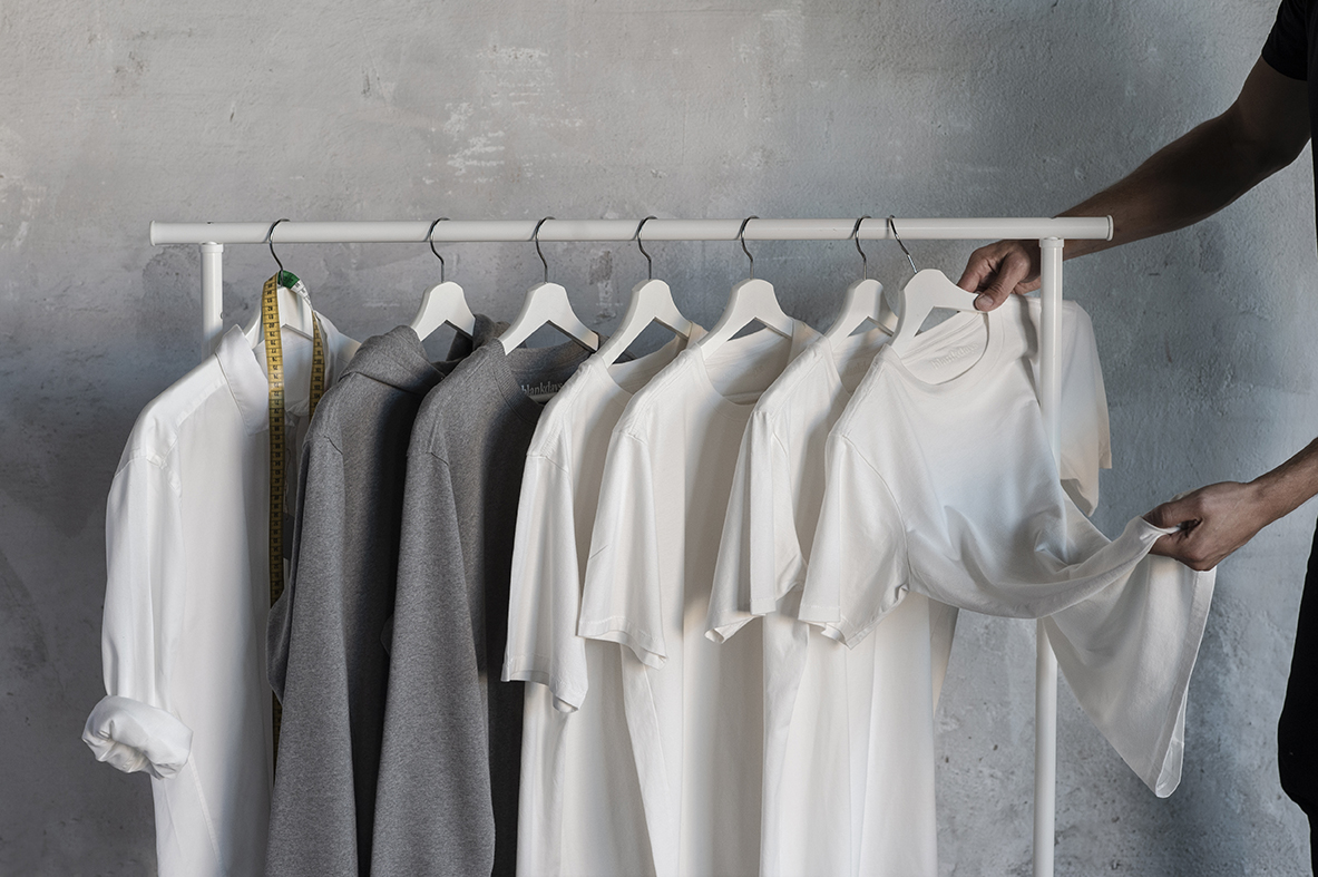 Den första kollektionen från Blankdays med skjortor och tshirts hänger på en vit klädställning.