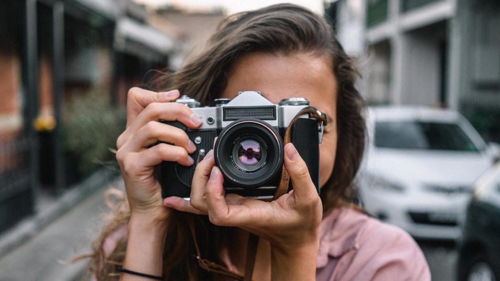 Närbild på en kvinna som tar en bild med en digital kompaktkamera.