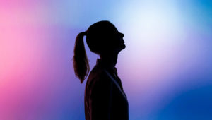 A dark silhouette of a woman standing in front of a purple and pink abstract background with a tech atmosphere.