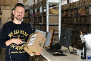 Erik Vaim som grundat företaget Footly står vid en kassa i en lagerlokal och scannar streckkoden på ett paket. 