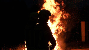 En brandman står framför en stor eldsvåda.
