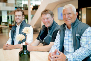 John, Peter och Lucas från Aridum sitter vid ett bord. Alla tre ler mot kameran.