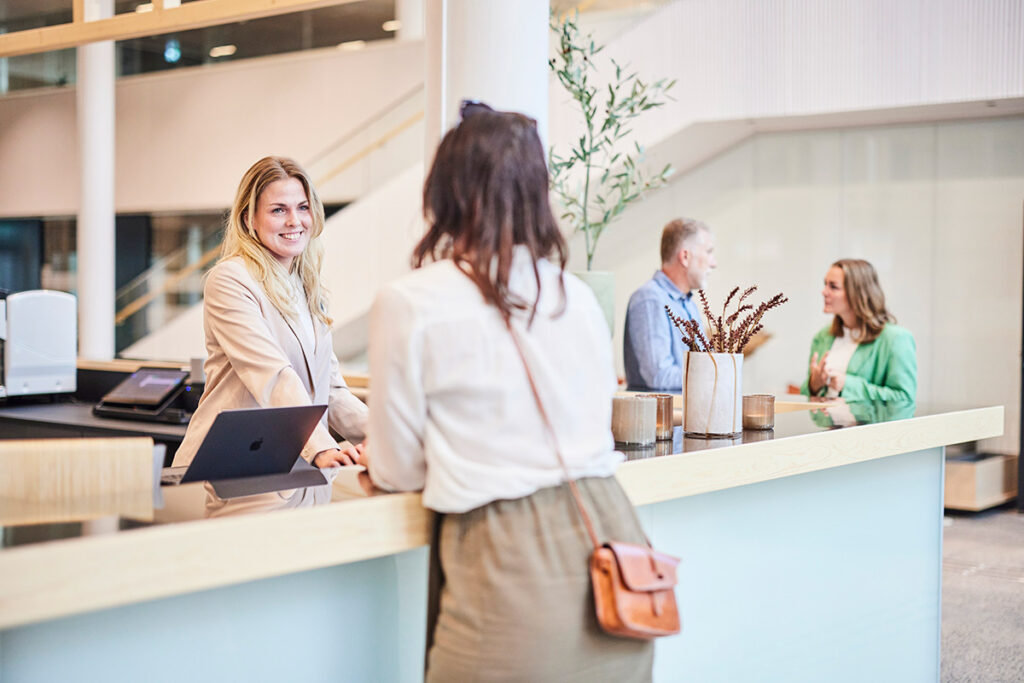 Maria och Jonna står vid receptionen och pratar,